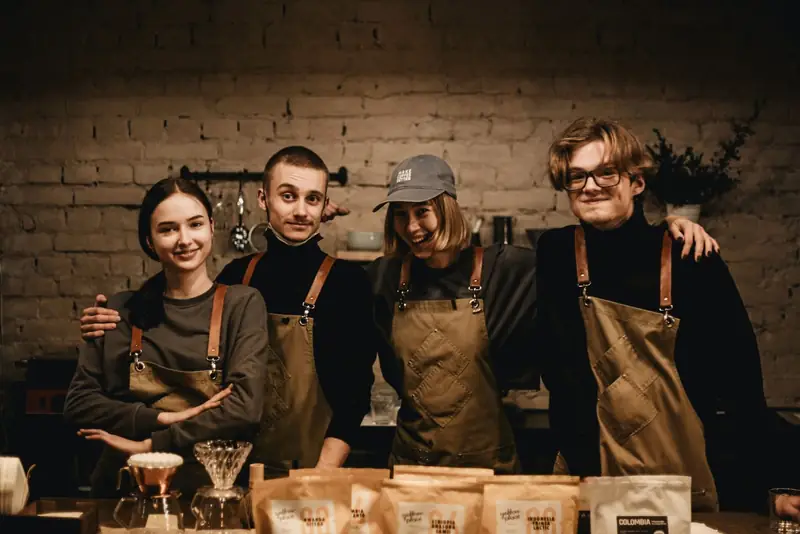 Four café staff in matching aprons behind the counter