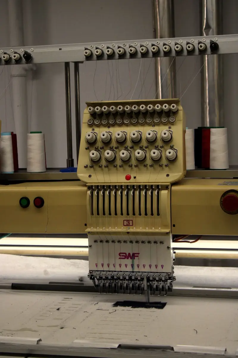Embroidery machine heads threaded with cones of colour