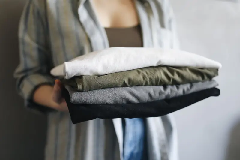 Hands holding a stack of folded T-shirts ready to go out