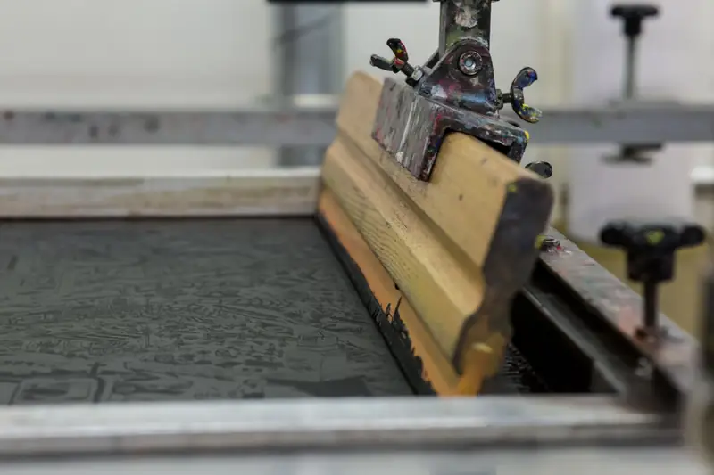 Wooden squeegee resting on a screen printing frame