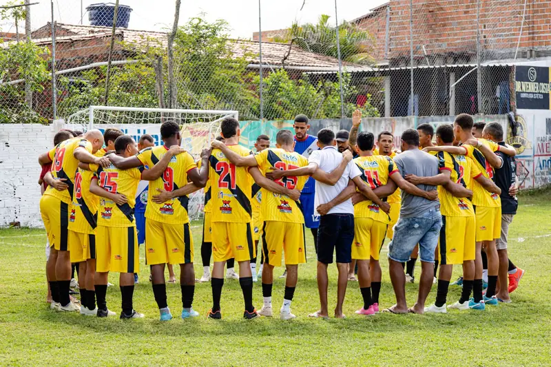 Football team in matching yellow kits huddled on the pitch